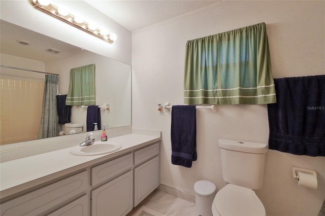 bathroom with toilet, vanity, and tile flooring