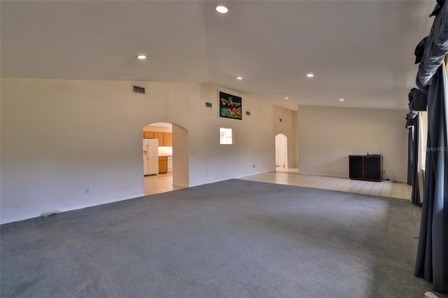 unfurnished living room with light carpet and vaulted ceiling