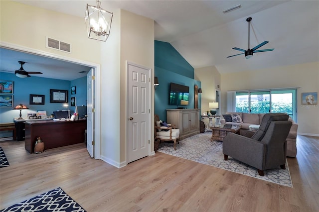 living room with high vaulted ceiling, ceiling fan with notable chandelier, and light wood-type flooring