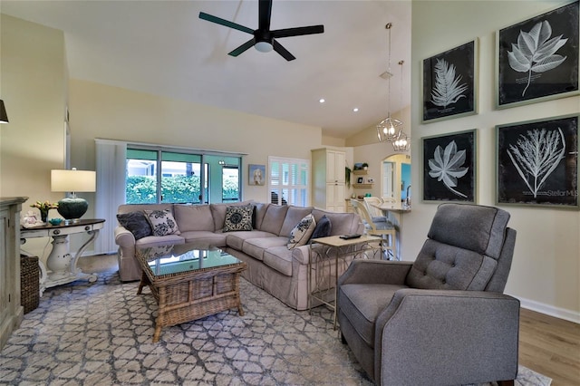 living room with light hardwood / wood-style flooring, high vaulted ceiling, and ceiling fan with notable chandelier