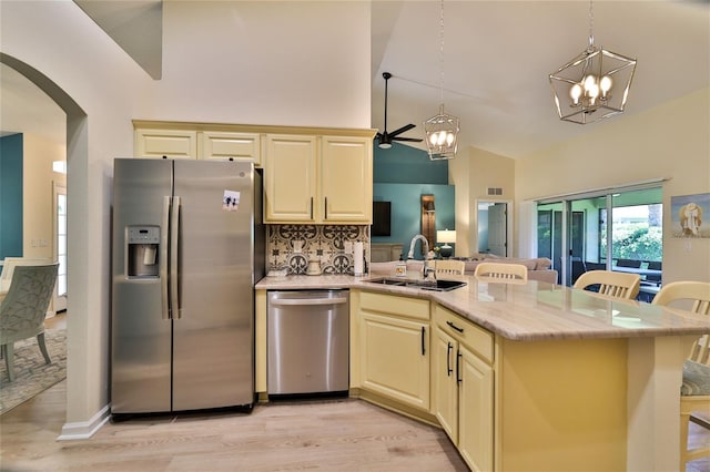 kitchen with pendant lighting, stainless steel appliances, light wood-type flooring, and sink