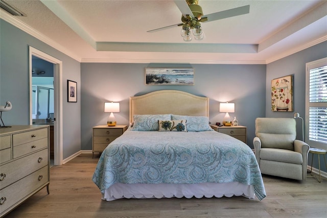 bedroom with a raised ceiling, ceiling fan, and light hardwood / wood-style flooring