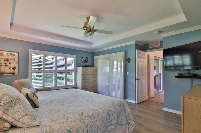 bedroom featuring a tray ceiling, ceiling fan, dark wood-type flooring, and crown molding