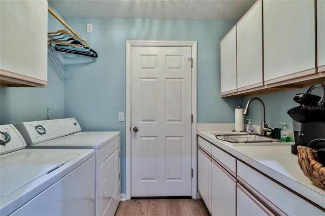 laundry room with sink, cabinets, a textured ceiling, washing machine and dryer, and light wood-type flooring