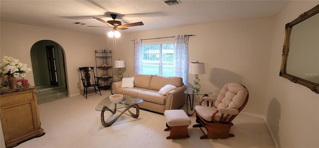 carpeted living room with a textured ceiling and ceiling fan