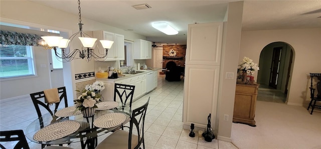 dining space with light carpet, a chandelier, sink, and a fireplace