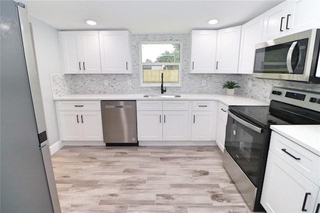 kitchen with white cabinetry, stainless steel appliances, light wood-type flooring, and sink