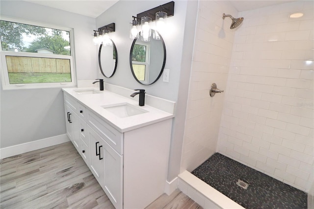 bathroom with dual vanity and a tile shower