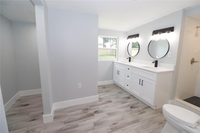 bathroom with vanity, a tile shower, wood-type flooring, and toilet