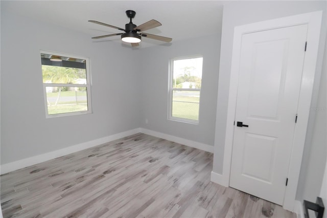 spare room featuring light hardwood / wood-style floors, ceiling fan, and a wealth of natural light