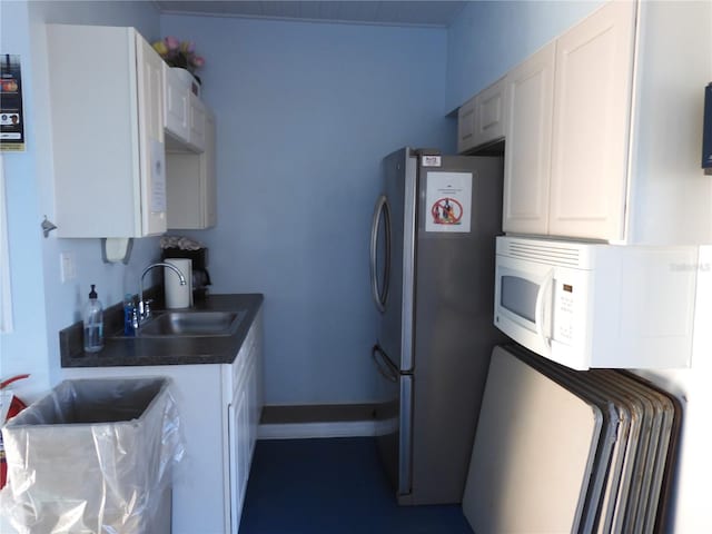 kitchen with white cabinetry, stainless steel fridge, and sink