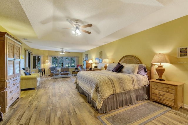 bedroom featuring a textured ceiling, ceiling fan, multiple windows, and wood-type flooring