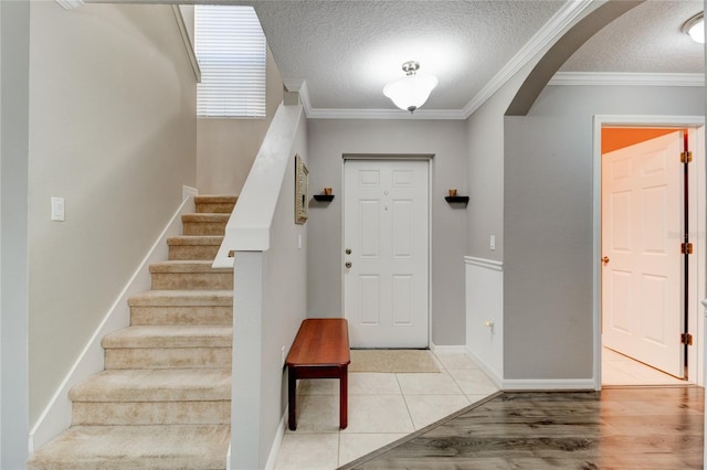 foyer entrance with light tile floors, a textured ceiling, and ornamental molding