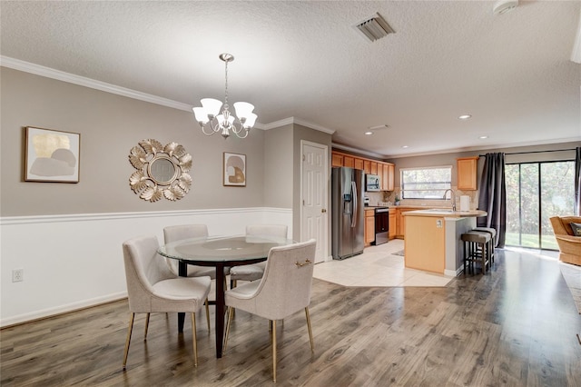 dining room with light tile floors, a notable chandelier, a textured ceiling, and crown molding