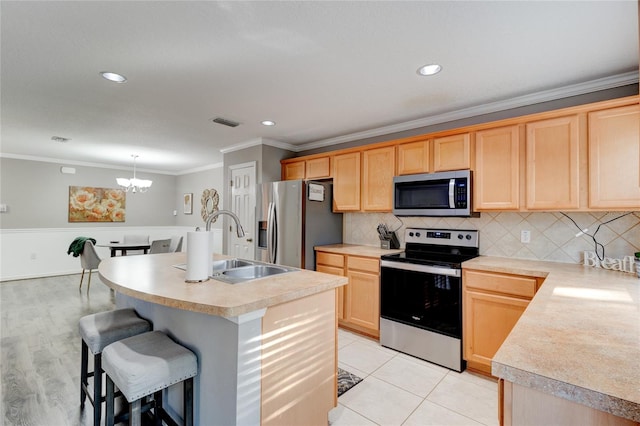 kitchen featuring an island with sink, ornamental molding, a chandelier, stainless steel appliances, and tasteful backsplash