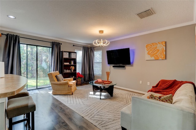 living room featuring a chandelier, a textured ceiling, ornamental molding, and light wood-type flooring