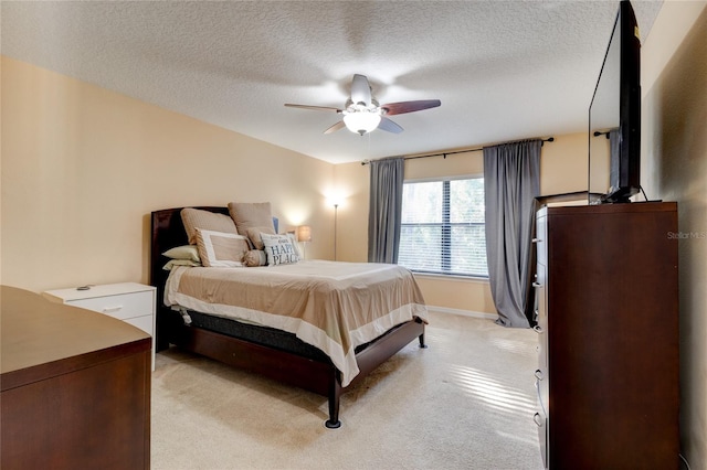 bedroom featuring a textured ceiling, light colored carpet, and ceiling fan