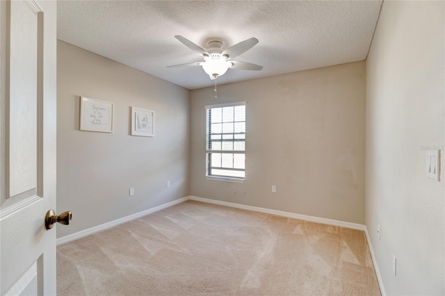 spare room featuring light colored carpet, ceiling fan, and a textured ceiling