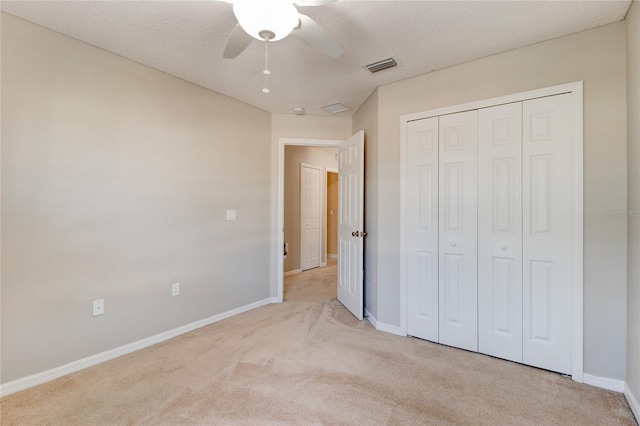 unfurnished bedroom featuring light carpet, a closet, ceiling fan, and a textured ceiling