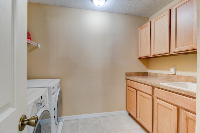 laundry area with cabinets, sink, light tile floors, a textured ceiling, and washer and dryer