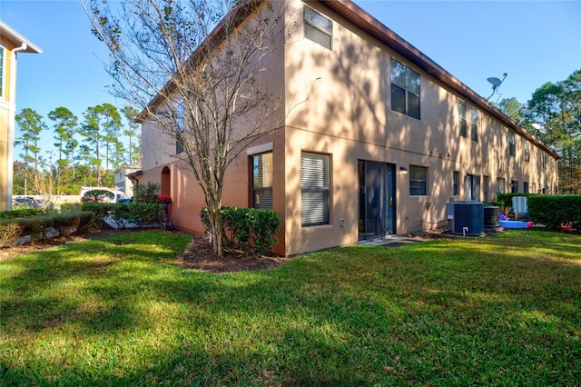 rear view of house featuring a lawn and central air condition unit