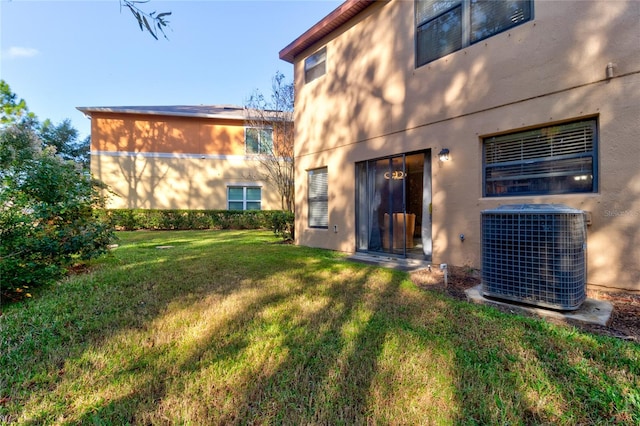 rear view of property with central AC unit and a yard