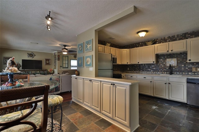 kitchen featuring ceiling fan, sink, dark tile flooring, appliances with stainless steel finishes, and a textured ceiling