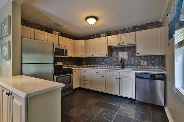 kitchen with dark tile flooring, tasteful backsplash, appliances with stainless steel finishes, and sink