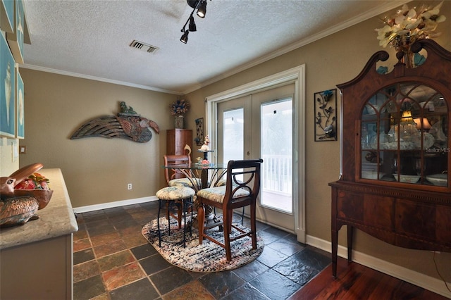 tiled dining room with a textured ceiling, rail lighting, crown molding, and french doors