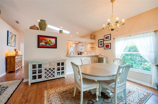 dining area featuring sink, a chandelier, dark wood-type flooring, and vaulted ceiling