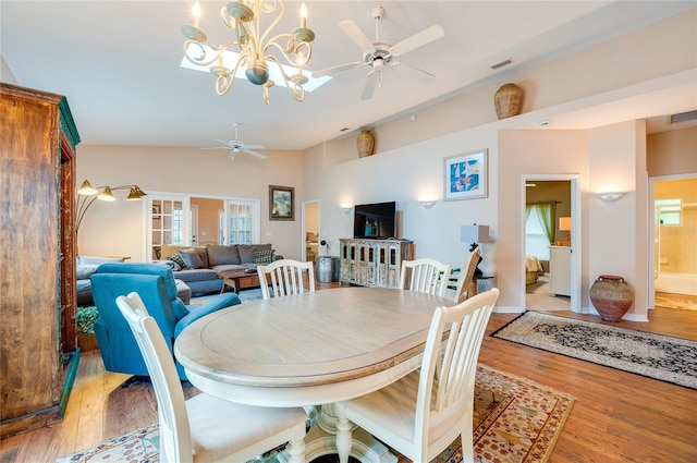 dining area with lofted ceiling, light hardwood / wood-style floors, and ceiling fan with notable chandelier