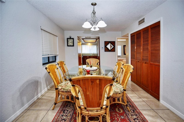 dining space featuring light tile floors, a notable chandelier, and a textured ceiling