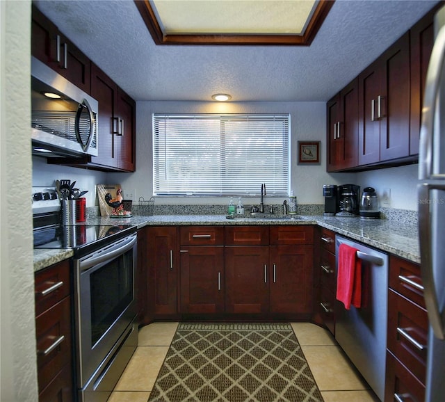 kitchen with light stone countertops, a textured ceiling, sink, and stainless steel appliances