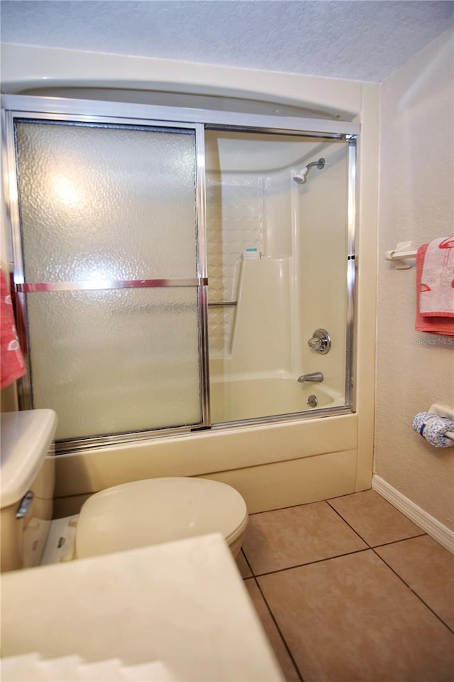 bathroom featuring enclosed tub / shower combo, toilet, and tile floors