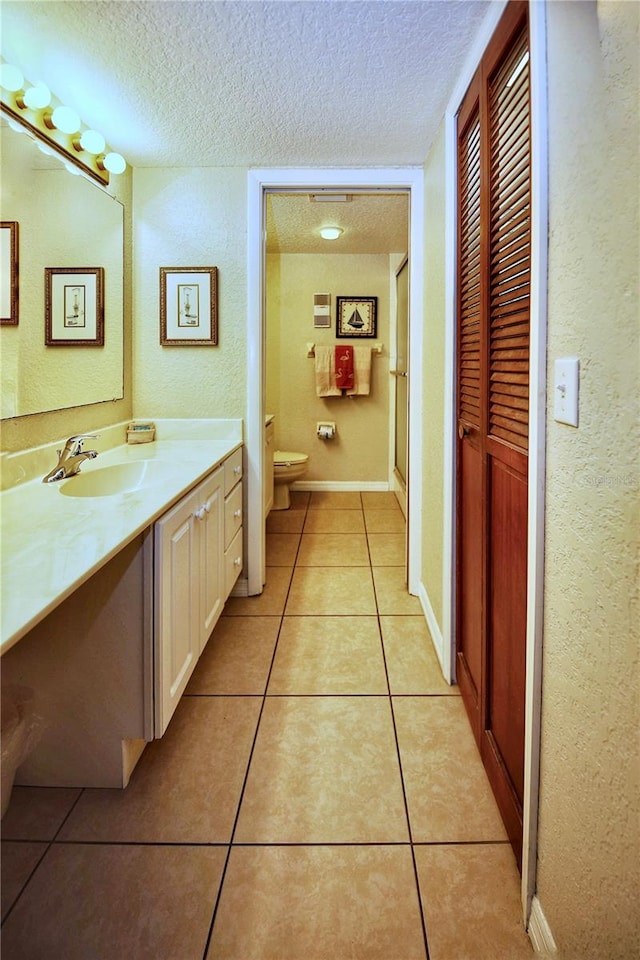 bathroom with vanity, a textured ceiling, tile floors, and toilet