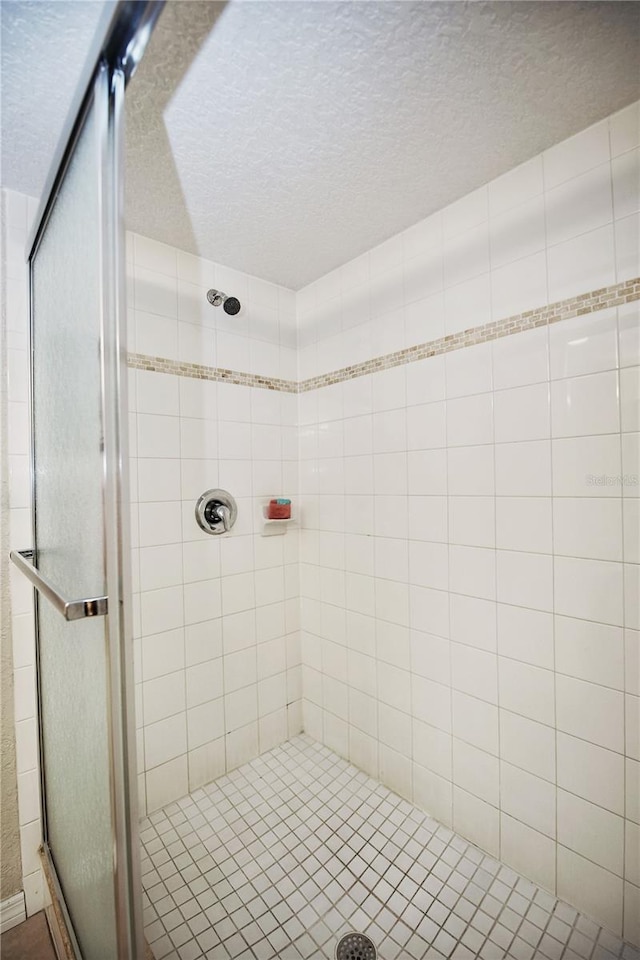 bathroom featuring an enclosed shower and a textured ceiling