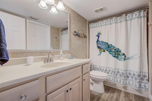 bathroom featuring toilet, vanity with extensive cabinet space, wood-type flooring, an inviting chandelier, and a textured ceiling