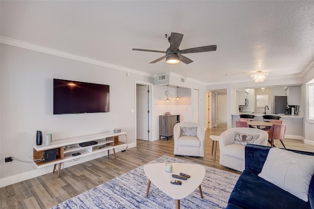 living room featuring a textured ceiling, light hardwood / wood-style floors, ceiling fan, and ornamental molding