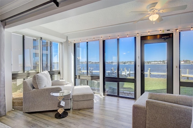 sunroom / solarium with ceiling fan and a water view