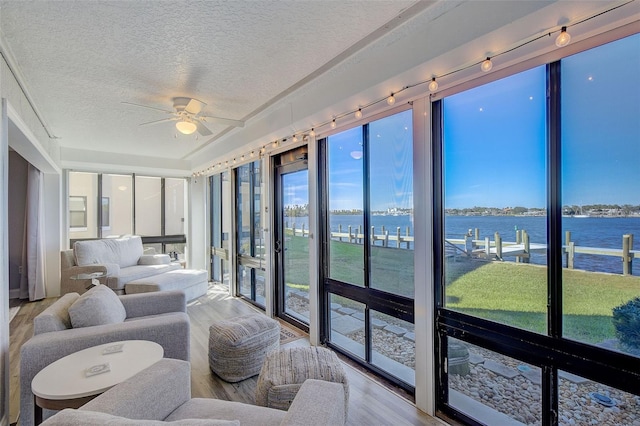 sunroom featuring track lighting, ceiling fan, and a water view