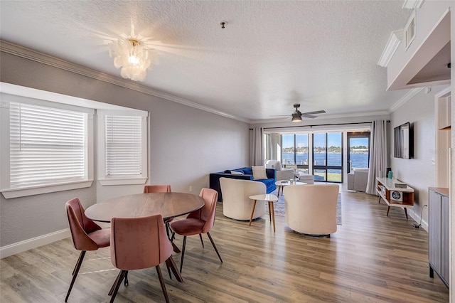 dining room with a textured ceiling, light hardwood / wood-style floors, ceiling fan, and a water view