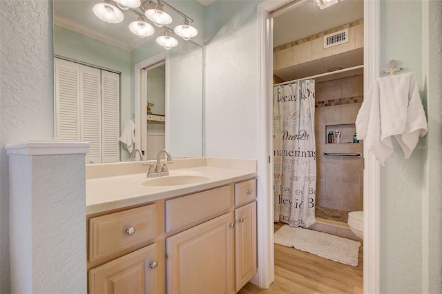 bathroom with toilet, ornamental molding, wood-type flooring, oversized vanity, and an inviting chandelier