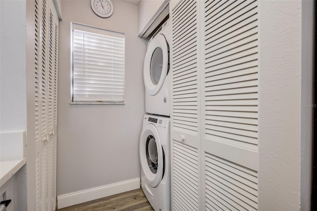 clothes washing area with stacked washer / dryer and dark wood-type flooring