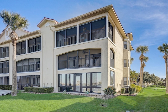 rear view of property featuring a lawn, a balcony, and central AC