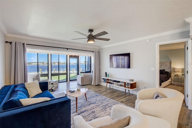 living room featuring a water view, ornamental molding, ceiling fan, and hardwood / wood-style floors