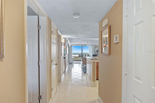 corridor with floor to ceiling windows, a textured ceiling, and light tile flooring