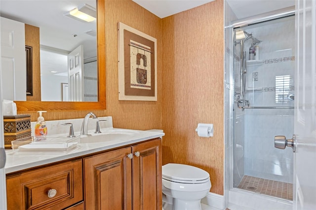 bathroom with toilet, vanity, and a shower with door