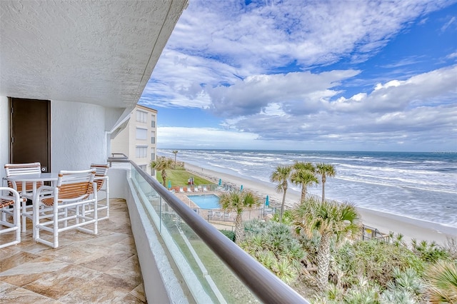 balcony with a water view and a view of the beach