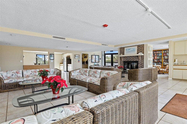 living room with a textured ceiling, a fireplace, track lighting, and light tile floors
