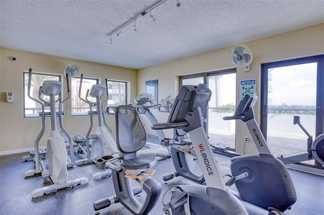 exercise room featuring plenty of natural light, a textured ceiling, and rail lighting